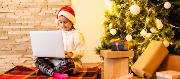 Ein Kleines Nettes Mädchen Mit Weihnachtsmütze Kommuniziert Online Mit Verwandten — Stockfoto