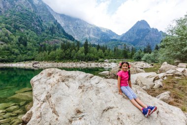 Küçük kız İtalya dağlarına bakıyor.