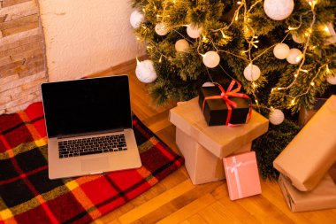 Boş beyaz ekranlı dizüstü bilgisayar hediyeler, Noel Baba evinin arka planında süslenmiş Noel ağacı. Etrade web sitesi online alışveriş dağıtım reklamları.