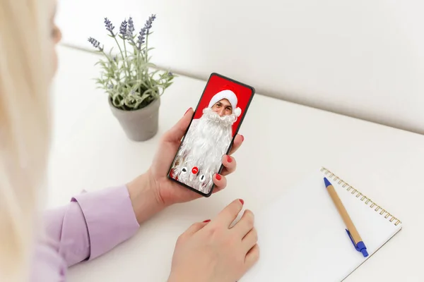 woman chatting on smartphone video chat with santa claus