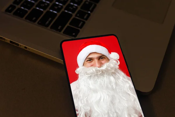 サンタクロースはスマートフォンを呼び出し 新年とメリークリスマスでビデオ挨拶を行います — ストック写真