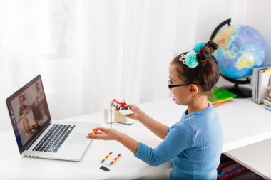 Küçük bilim adamı yeni bir proje üzerinde çalışıyor. Küçük kız internette robot bilimi okuyor.