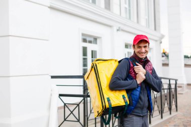 Eve servis için sarı termo çantalı bir teslimatçı. Eve yakın bir yerde. Kopyalamak için boş bir yer var.