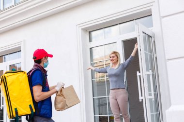 Termal sırt çantalı kurye genç bir iş kadınına taze yemek getiriyor. Restoran yemeği teslimatı konsepti