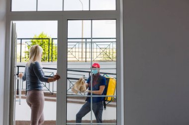 Termal sırt çantalı kurye genç bir iş kadınına taze yemek getiriyor. Restoran yemeği teslimatı konsepti