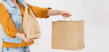 Kırmızı şapkalı kadın fast food siparişi veriyor. Kadın kurye, elinde yiyecek paketi tutuyor. Dükkan ya da restorandan eve ürün teslimatı. Boşluğu kopyala