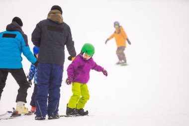 Snowboard Kış Sporu. Küçük kız snowboard öğreniyor, kalın kışlık giysiler giyiyor. Kış arkaplanı.