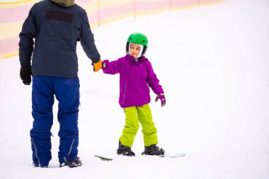 Soğuk Rüzgâr Günü 'nde Dağ Kayağı Tatil Köyü' nde Baba Küçük Kızına Snowboard öğretiyor