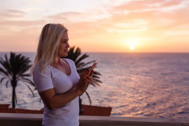 Balkondan gün batımına hayran bir kadın.