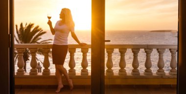 Balkondan gün batımına hayran bir kadın.