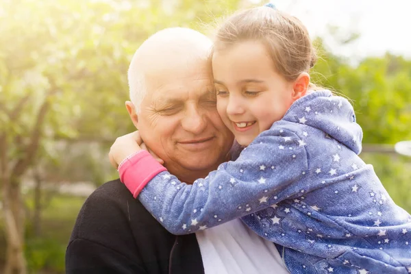 Arka bahçede büyükbabasıyla duran küçük bir kızın portresi..