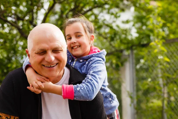 Arka bahçede büyükbabasıyla duran küçük bir kızın portresi..