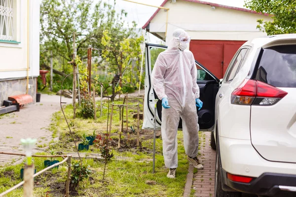 Man in protective suit, medical mask and rubber gloves for protect from bacteria and virus is driving a car. Protective mask while quarantine, world pandemic, covid 19, coronavirus, infection.