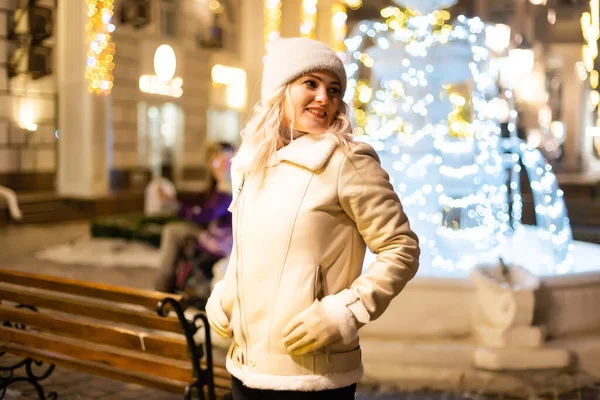 お祝いのクリスマスフェアで笑顔の美しい若い女性のストリートポートレート 古典的なスタイリッシュな冬のニットの服を着て女性 — ストック写真