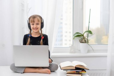 Evde bilgisayarını kullanarak internetten ders çalışan küçük bir kız.