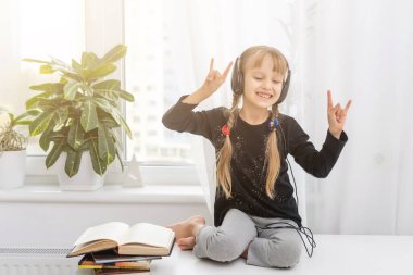 Evdeki masada oturan kulaklıklı sevimli küçük kız.