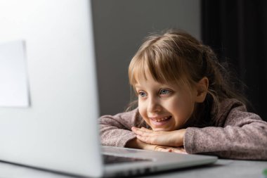 Evde bilgisayarını kullanarak internetten ders çalışan küçük bir kız.