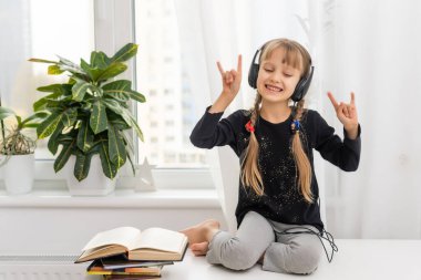 Sarı saçlı, kulaklıklı çocuk müzik dinliyor. Sosyal uzaklık. Karantina ve salgın.