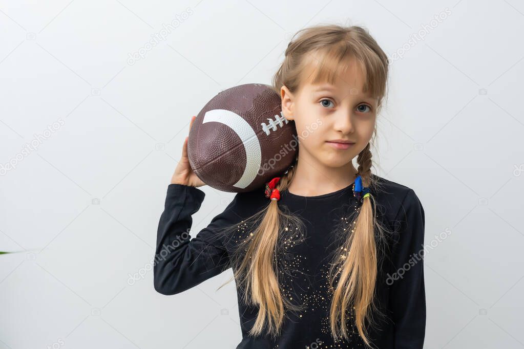 Little girl holding a rugby ball.