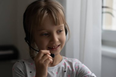 Evde bilgisayarda görüntülü konuşma yapan küçük bir kız. Metin için boşluk