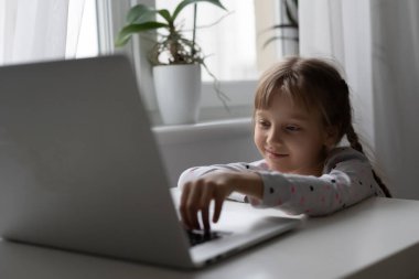 Evde bilgisayarını kullanarak internetten ders çalışan küçük bir kız.