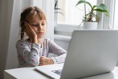 Evde bilgisayarını kullanarak internetten ders çalışan küçük bir kız.