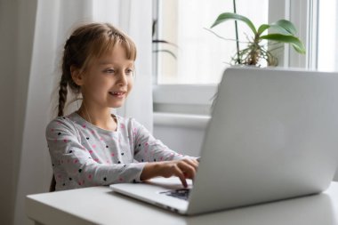 Evde bilgisayarını kullanarak internetten ders çalışan küçük bir kız.