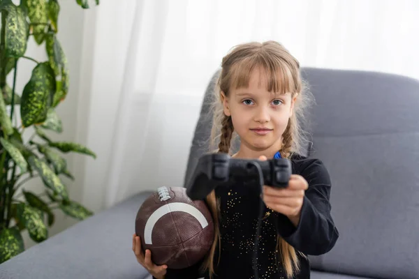 Κοριτσάκι Μπάλα Ράγκμπι Και Χειριστήριο Για Παίζετε Βιντεοπαιχνίδια Στο Σπίτι — Φωτογραφία Αρχείου