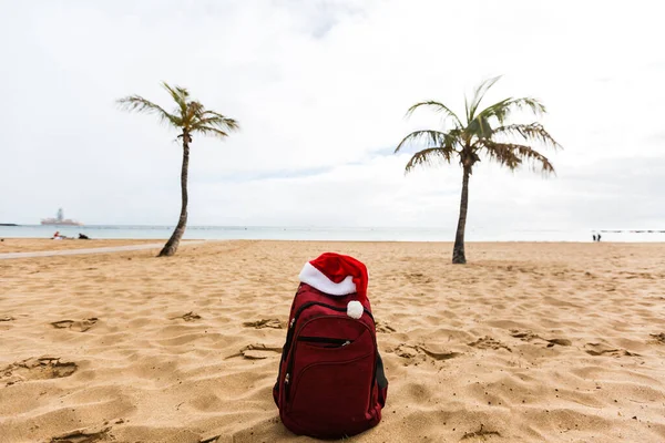 Kapelusz Świętego Mikołaja Plecaku Stojący Plaży Święta Nowy Rok Nikt — Zdjęcie stockowe