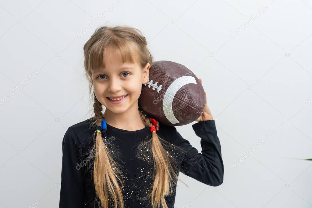Little girl holding a rugby ball.
