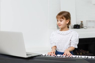 Karantina sırasında piyano öğrenen küçük bir kız. Coronavirus konsepti.