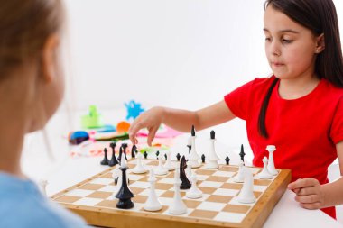 Evde satranç oynayan iki küçük kız kardeş.