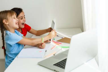 Evdeki online dersi sırasında öğrenim gören oldukça şık liseli kızlar, karantina sırasındaki sosyal mesafeler, kişisel izolasyon, online eğitim konsepti