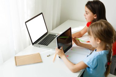 Havalı online okul. Çocuklar evde dizüstü bilgisayar kullanarak ders çalışıyor. Çevrimiçi e-öğrenme sisteminde çalışırken dizüstü bilgisayar kullanan neşeli küçük kızlar. Uzaktan öğrenme