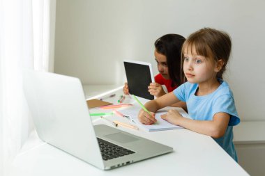 Evdeki online dersi sırasında öğrenim gören oldukça şık liseli kızlar, karantina sırasındaki sosyal mesafeler, kişisel izolasyon, online eğitim konsepti