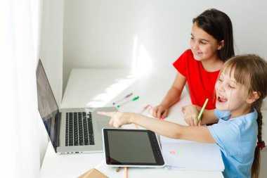 Evdeki online dersi sırasında öğrenim gören oldukça şık liseli kızlar, karantina sırasındaki sosyal mesafeler, kişisel izolasyon, online eğitim konsepti