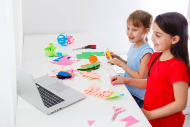 Havalı online okul. Çocuklar evde dizüstü bilgisayar kullanarak ders çalışıyor. Çevrimiçi e-öğrenme sisteminde çalışırken dizüstü bilgisayar kullanan neşeli küçük kızlar. Uzaktan öğrenme