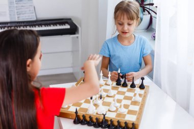 Evde satranç oynayan iki küçük kız kardeş.