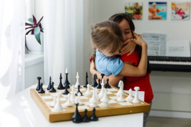 Evde satranç oynayan iki küçük kız kardeş.