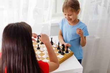 Evde satranç oynayan iki küçük kız kardeş.
