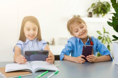 Evdeki online dersi sırasında öğrenim gören oldukça şık liseli kızlar, karantina sırasındaki sosyal mesafeler, kişisel izolasyon, online eğitim konsepti