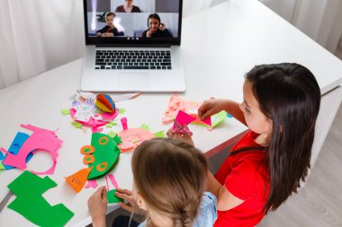 Evdeki online dersi sırasında öğrenim gören oldukça şık liseli kızlar, karantina sırasındaki sosyal mesafeler, kişisel izolasyon, online eğitim konsepti