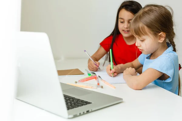 两个年龄最大 年龄最小的女孩在笔记本电脑上的一张桌子前订婚 — 图库照片