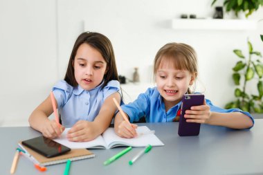 Evdeki online dersi sırasında öğrenim gören oldukça şık liseli kızlar, karantina sırasındaki sosyal mesafeler, kişisel izolasyon, online eğitim konsepti