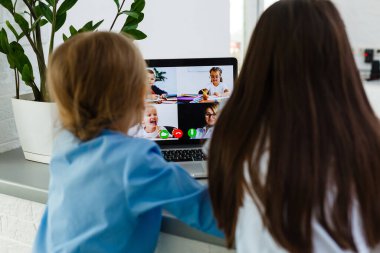 Havalı online okul. Çocuklar evde dizüstü bilgisayar kullanarak ders çalışıyor. Çevrimiçi e-öğrenme sisteminde çalışırken dizüstü bilgisayar kullanan neşeli küçük kızlar. Uzaktan öğrenme