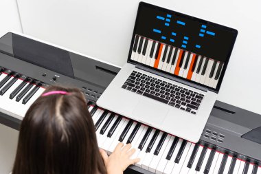 Küçük bir kız video derslerinden piyano çalmayı öğreniyor. covid-19 sırasında çevrimiçi uzaklık öğrenimi