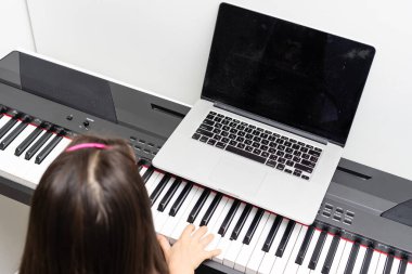 Küçük bir kız video derslerinden piyano çalmayı öğreniyor. covid-19 sırasında çevrimiçi uzaklık öğrenimi