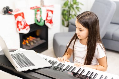 Küçük kız, Noel zamanı piyano çalma konusunda öğretmeniyle çevrimiçi ders alıyor.