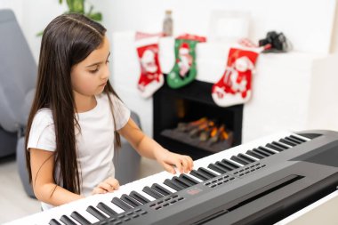 Tatlı küçük kız piyanoda Noel melodisi çalar, mutlu Noel kutlaması, mutlu mevsimsel tatiller
