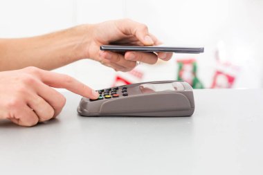 Temassız cep telefonu ödemesi. Ödeme terminali ve akıllı telefon ellerinde.